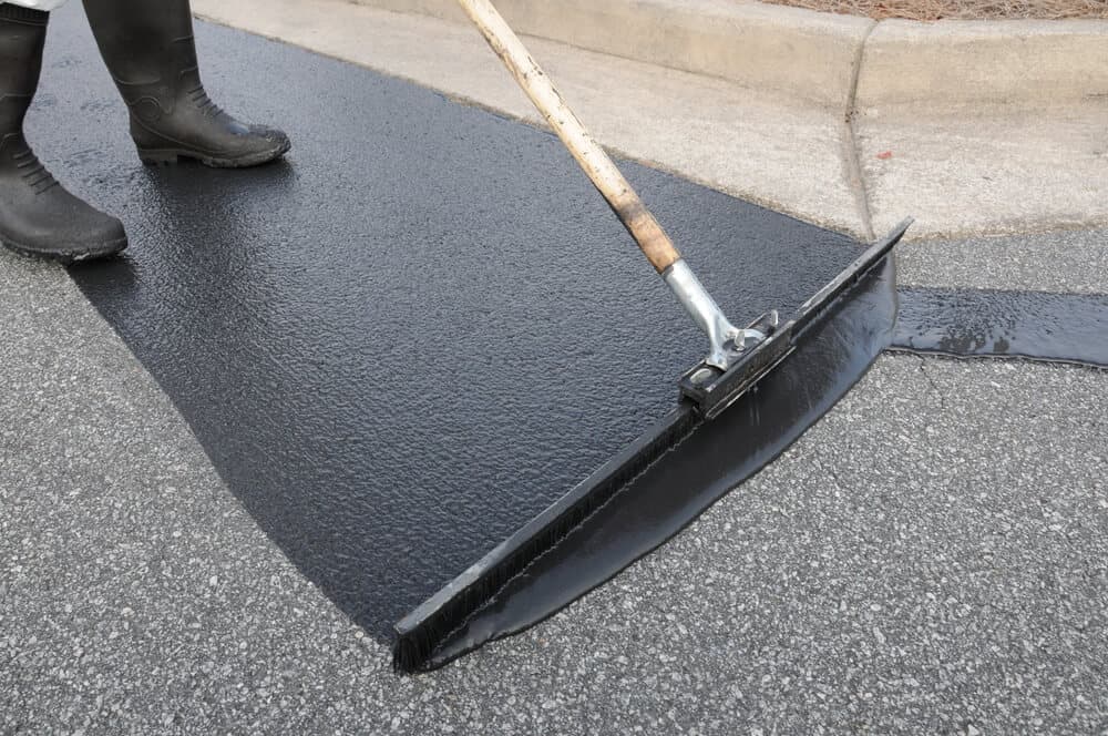 Close up of driveway sealant being applied with a squeegee brush